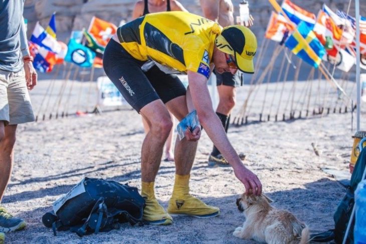 Maratonista acariciando a cachorrita mientras ésta descansa