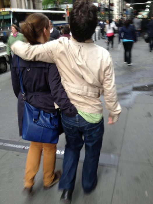 Hombre y mujer caminando mientras la mujer tiene su mano adentro del pantalón de él