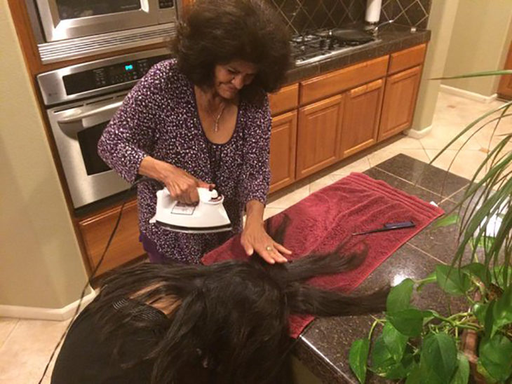 señora planchando el pelo a muchacha