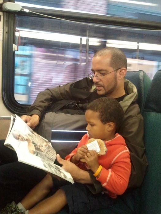 hombre leyendo un libro a un niño en un autobús