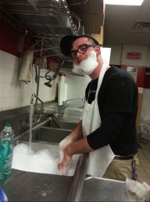 chico lavando los platos tiene barba de espuma