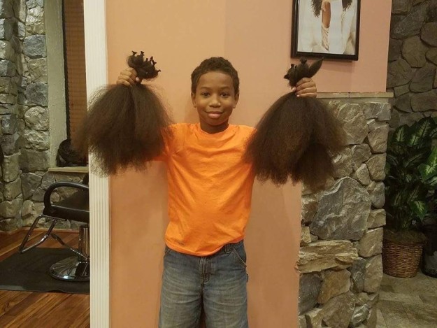 Niño dona su cabello - sosteniendo los dos mechones