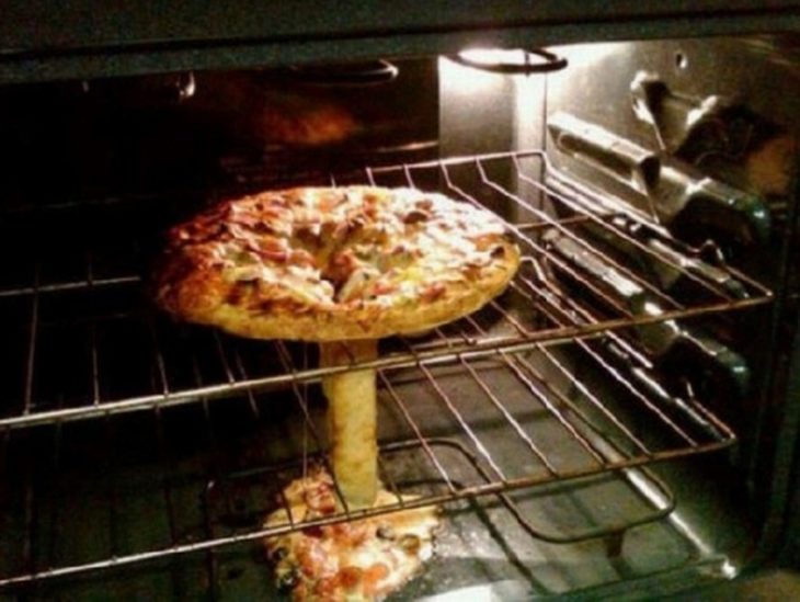 Pizza en el horno con un hoyo en el centro chorreando todo el queso