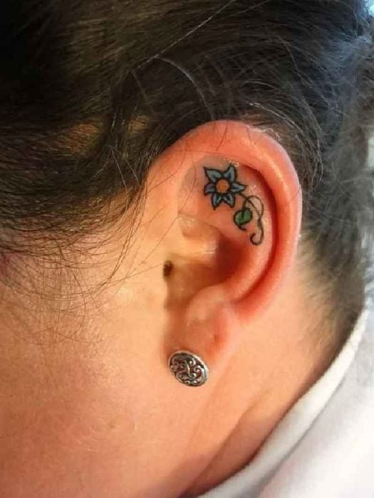 Tatuaje de una flor azul adentro del oído