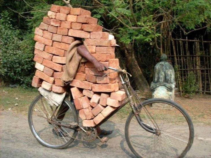 señor en bicicleta cargando con ladrillos