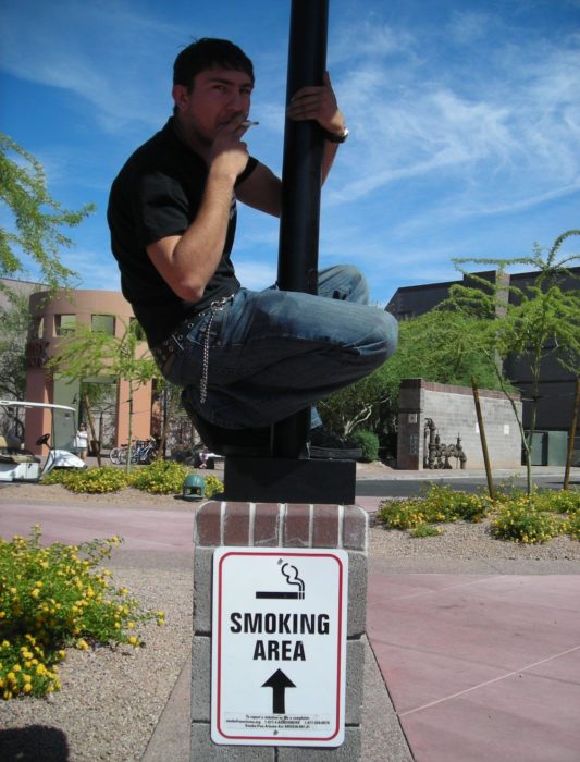 hombre fumando en un poste