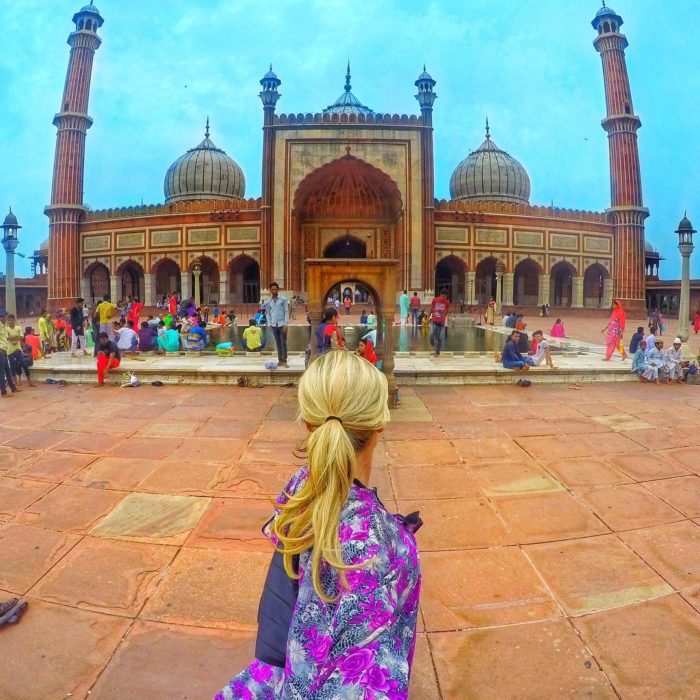 mujer frente a un hermoso edificio de la india 