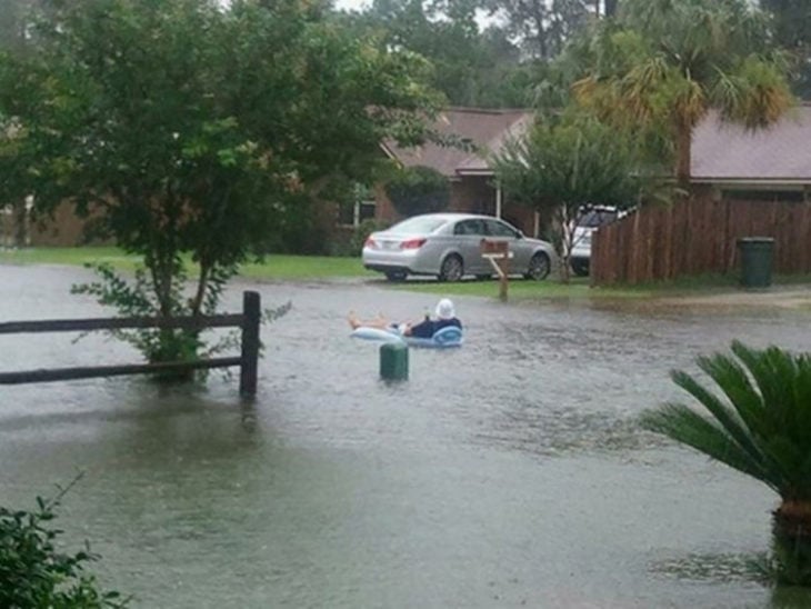 hombre en inflable sobre calle inundada 