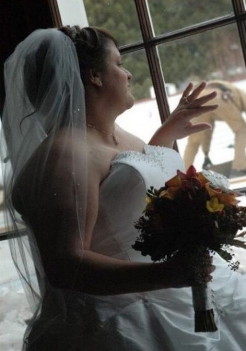 novia mirando a la ventana por fuera el novio está empinado