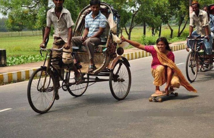 mujer hindú en patineta sostenida de una carreta de bicicletas