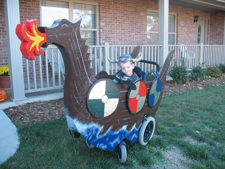 niño en silla de ruedas decorada como barco vikingo