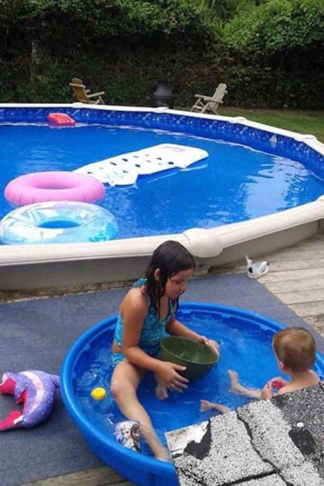 niños en una alberca pequeña mientras hay una piscina grande cerca