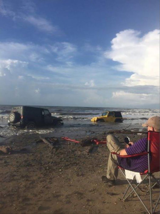 hombre se sienta a observar como se hunden las camionetas