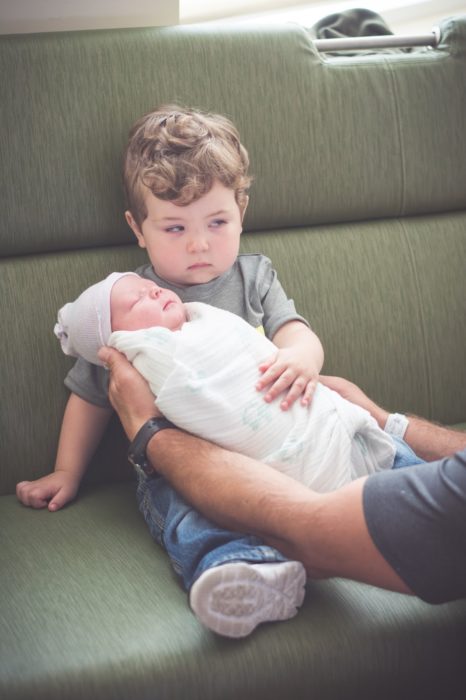 niño enojado cargando a su hermano bebé