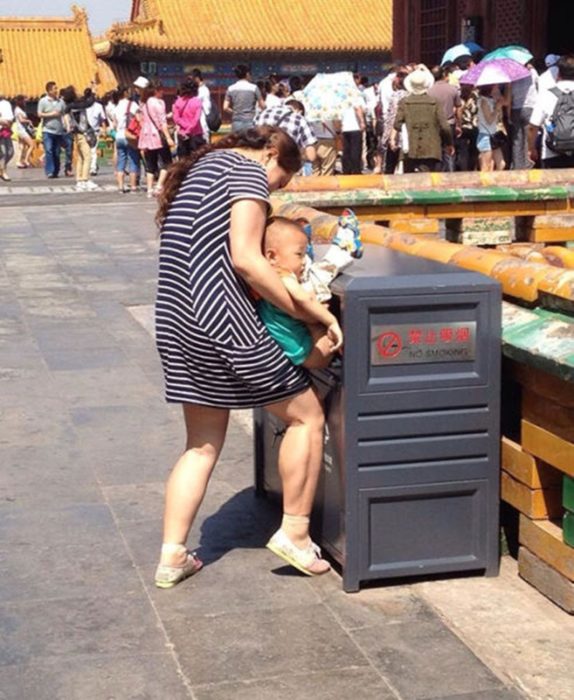 señora con bebé en el bote de basura