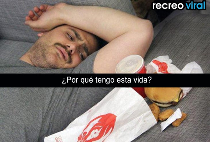 hombre recostado al lado de hamburguesas y papitas