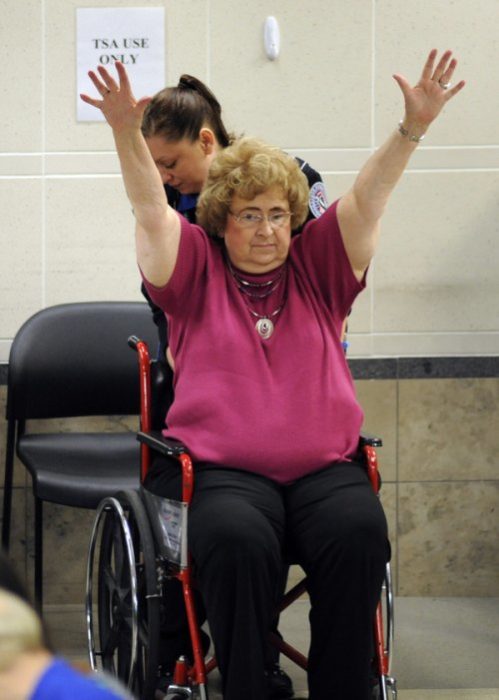 señora en silla de ruedas con las manos arriba pasando punto de revisión en el aeropuerto 