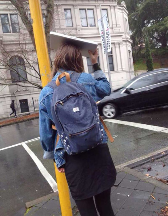 muchacha tapándose de la lluvia con una laptop