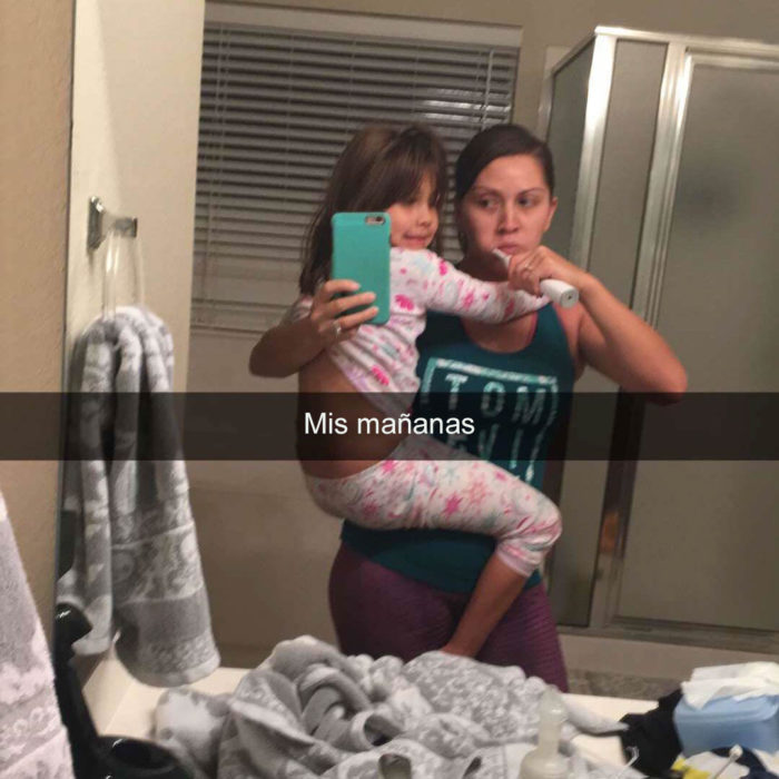 Papás cansados - mujer lavandose los dientes cargando a su hija