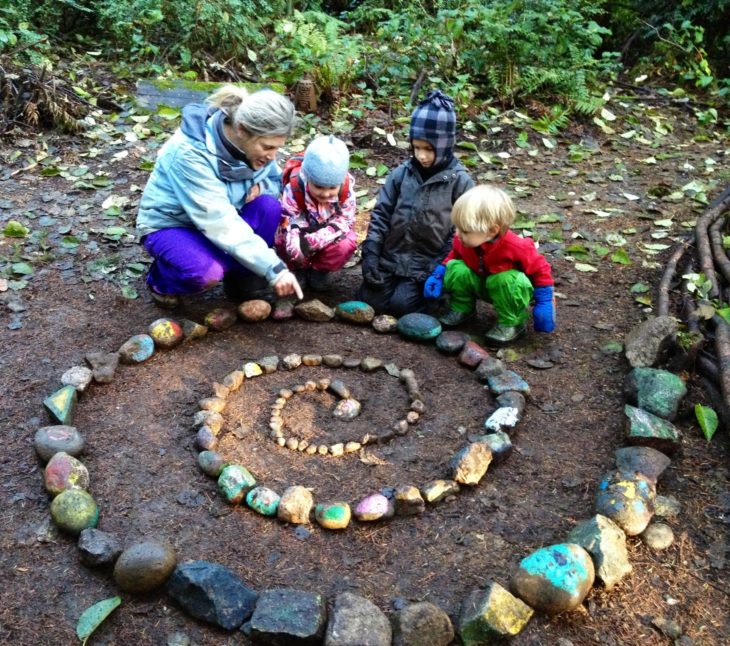 niños en bosque poniendo piedras en espiral