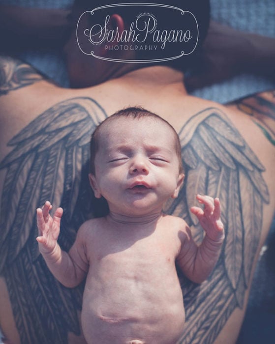bebé en la espalda de su papá que tiene tatuadas unas alas 