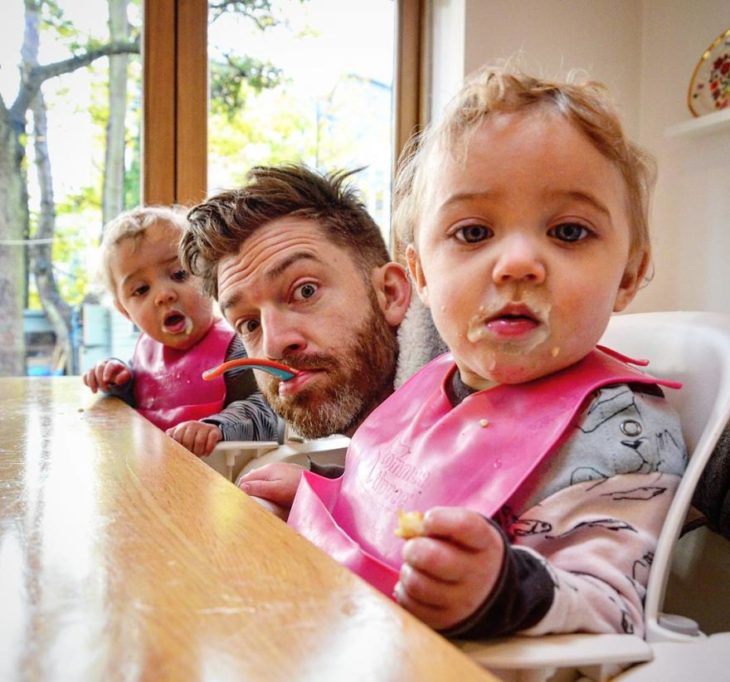 papá con gemelas bebés sentados a la mesa