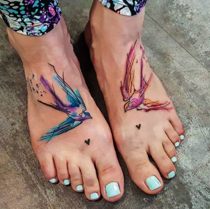 tatuaje estilo acuarela de aves en los pies de una mujer