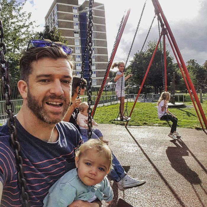 papá con sus hijas en los columpios