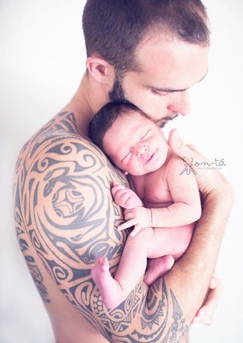 bebé sonríe mientras su papá lo carga