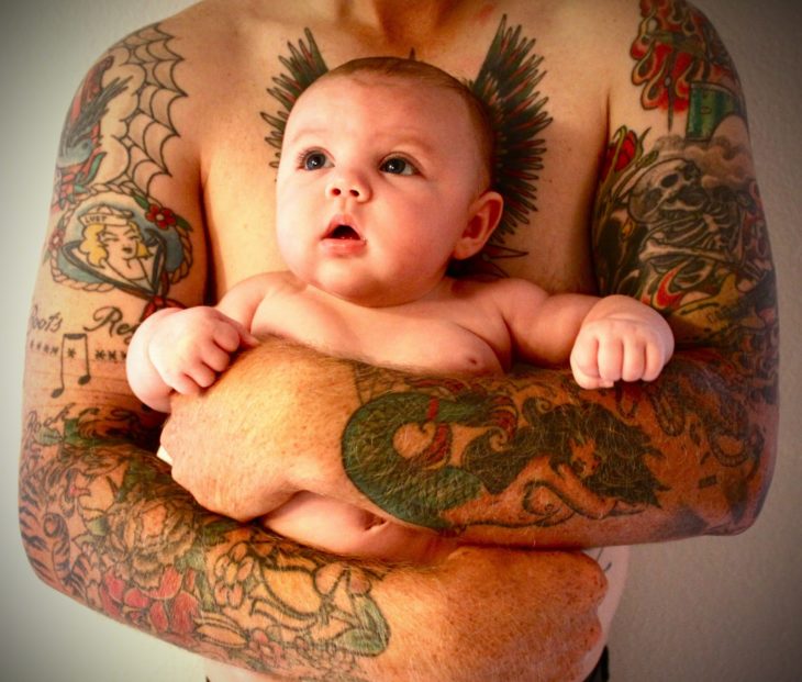 bebé en los brazos de su papá tatuado 