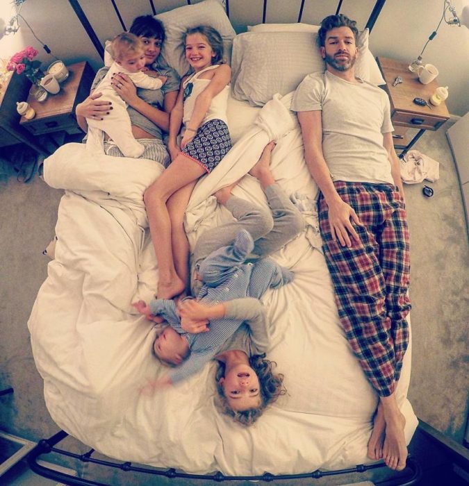 familia de esposo, esposa y cuatro hijas en la cama