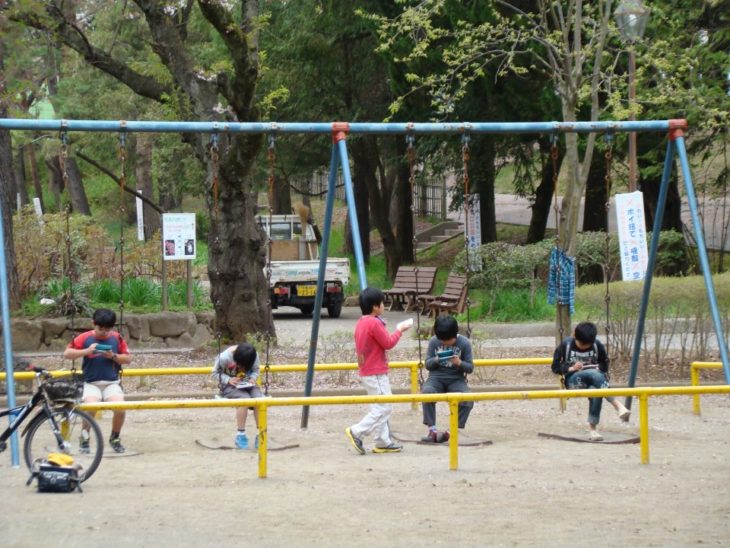 niños mirando sus tabletas en columpios