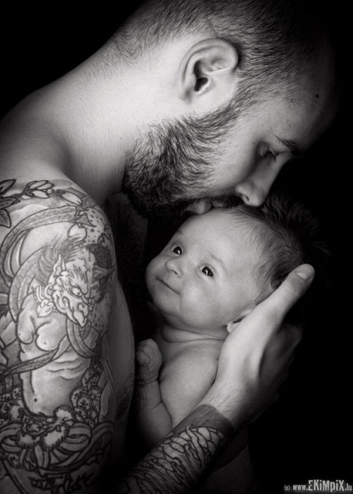 papá tatuado besando a su bebé