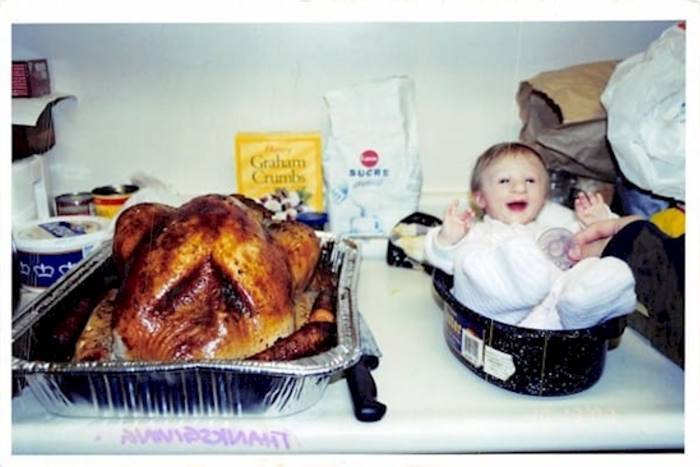 bebé pequeña al lado de un pollo asado