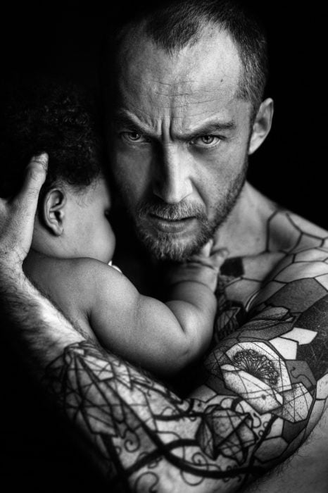 hombre con barba tatuado cargando a su bebé 