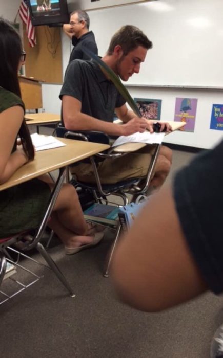 muchacho en salón de clase escribiendo con una pluma de pájaro