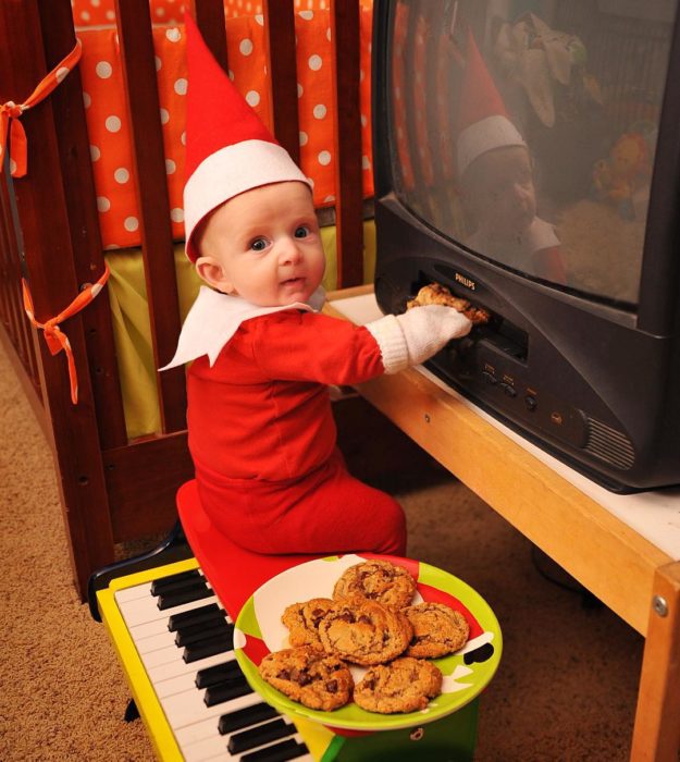 bebé vestido de elfo metiendo galletas a un dvd