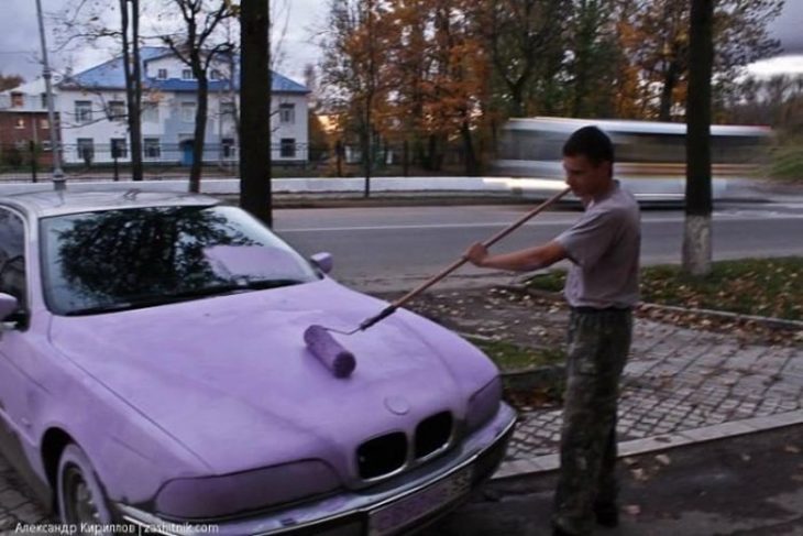 hombre pintando de lila un coche