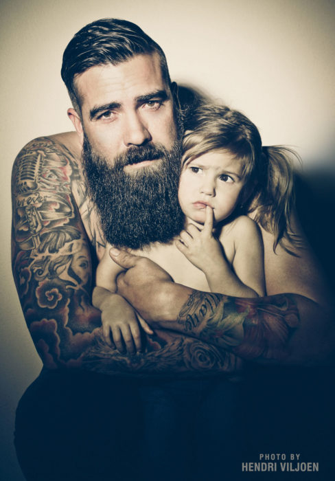 señor tatuado con barba y una niña 