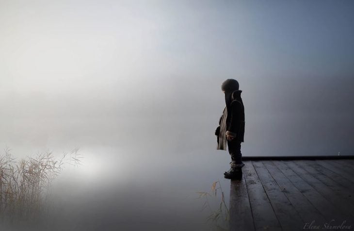 niño al lado de un lago