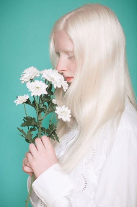 Mujer albina oliendo flores