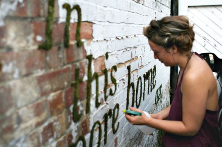 Mujer regando su graffiti de musgo 