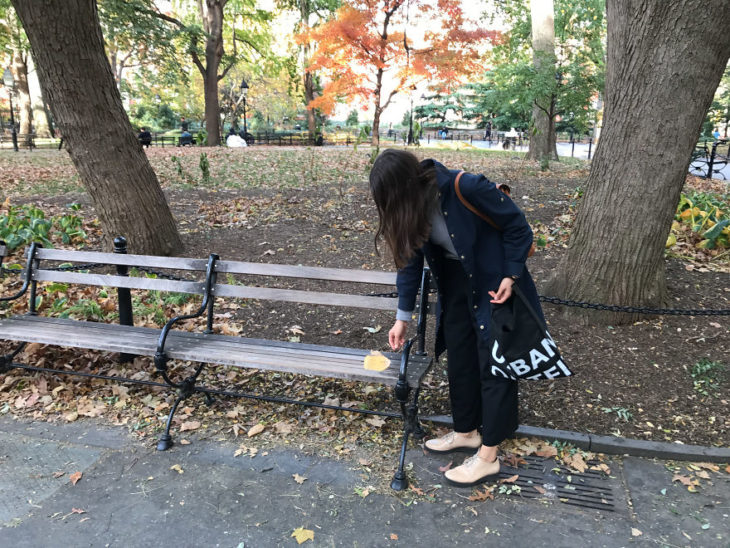 Una jóven colocando hojas con poesía en los parques