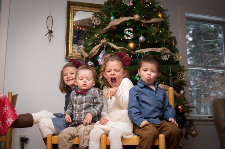 cuatro niños frente a un árbol de navidad