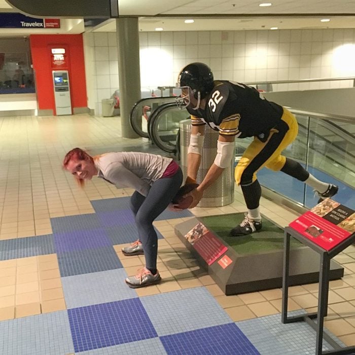 mujer posa con una estatua de jugador americano