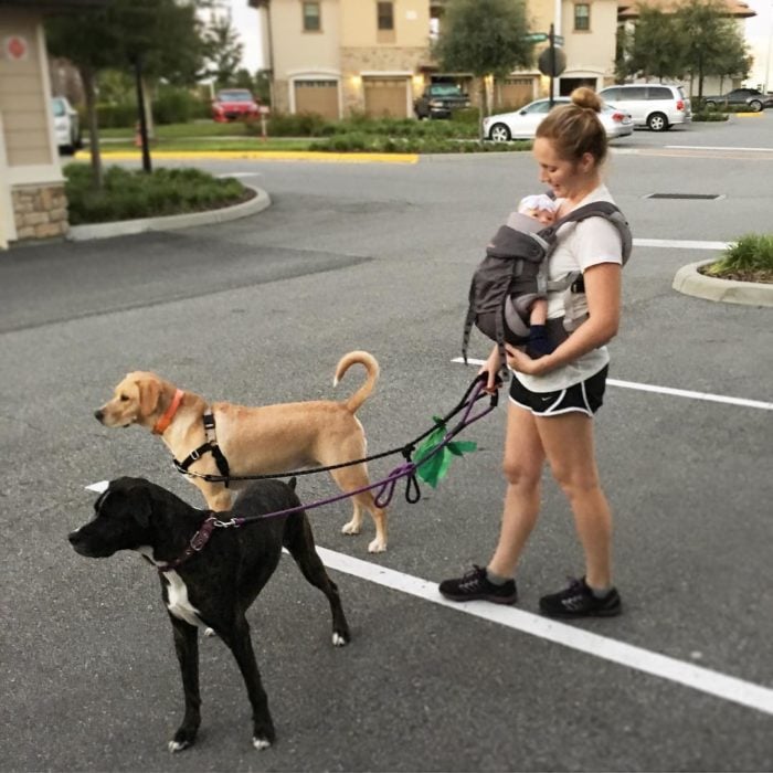 mujer cargando bebé caminando con perros