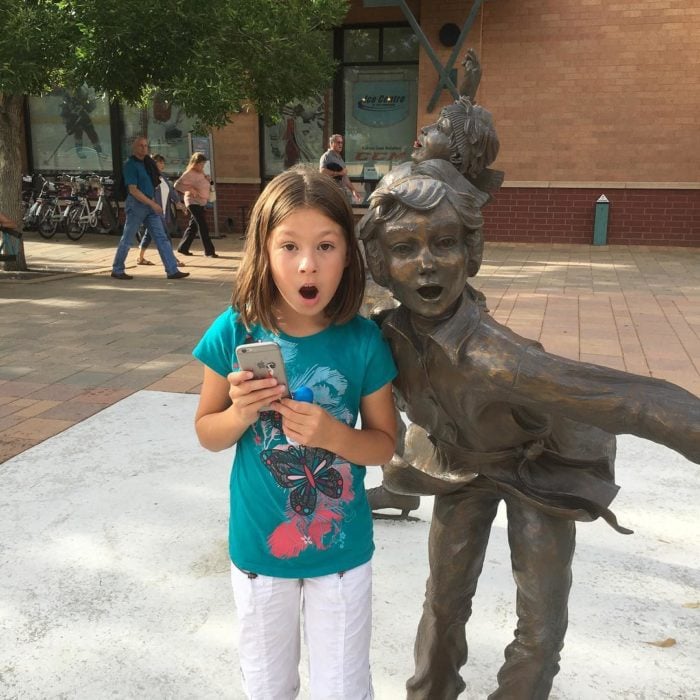 niña con expresión de sorpresa posa con estatua con expresión de sorpresa