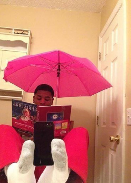 muchacho leyendo un libro con un paraguas rosa se toma selfie con los pies