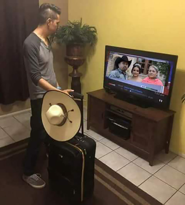 hombre con una maleta mirando el tv