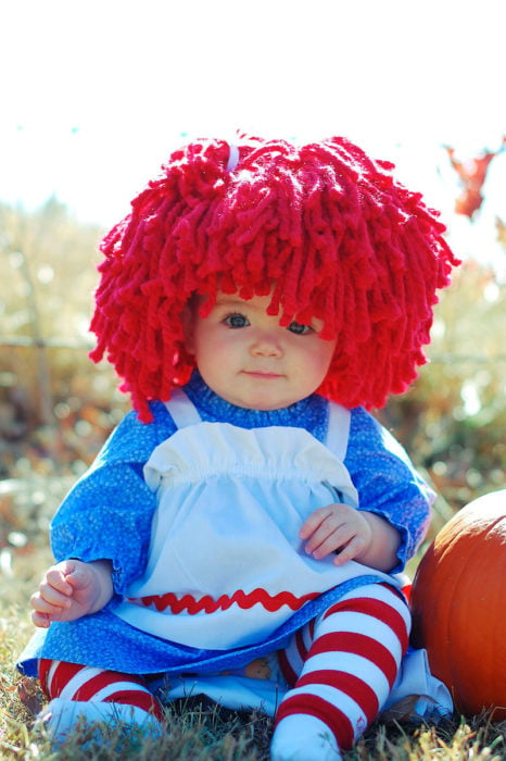 niña vestida de muñeca con peluca de estambre